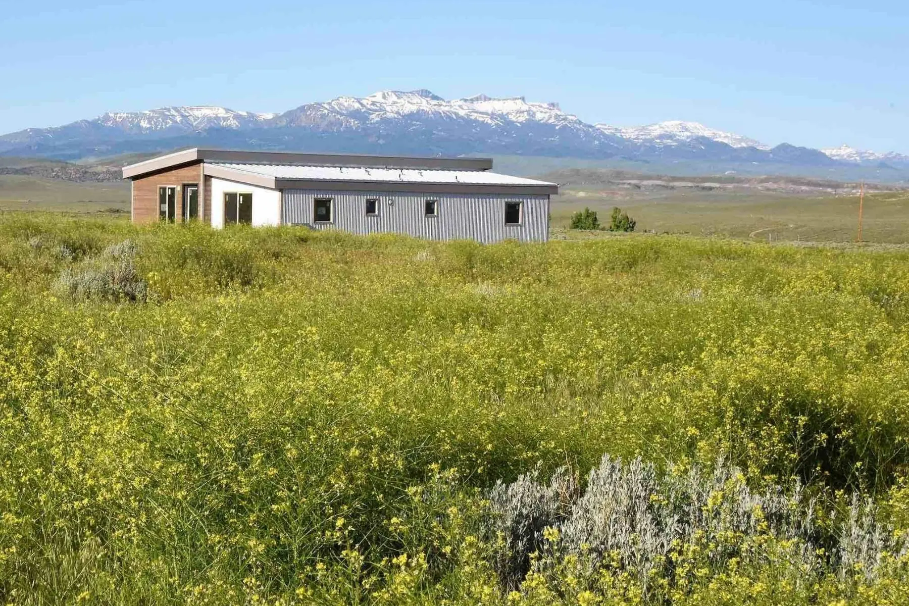 IdeaBox Sage House sustainable prefab housing out in a field with mountains in the distance