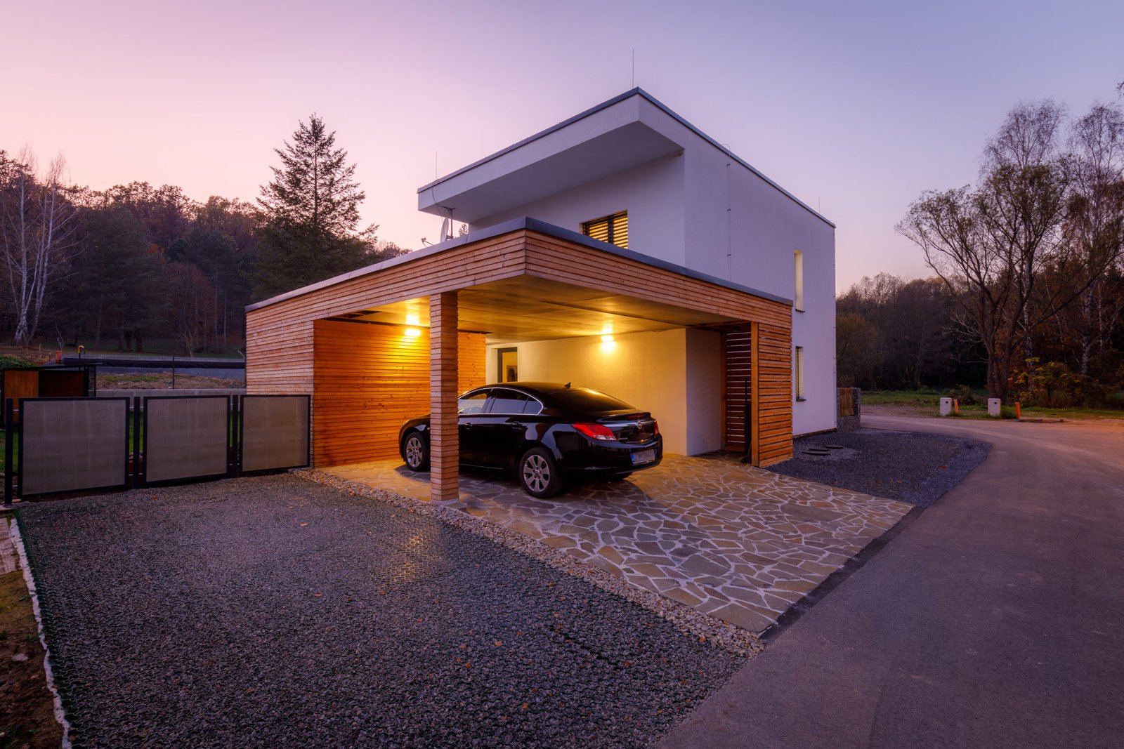 Prefab house exterior at dusk with car parked under carport