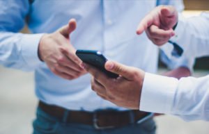 2 businessmen looking at a phone discussing carbon offsets, Greenwashing and climate change