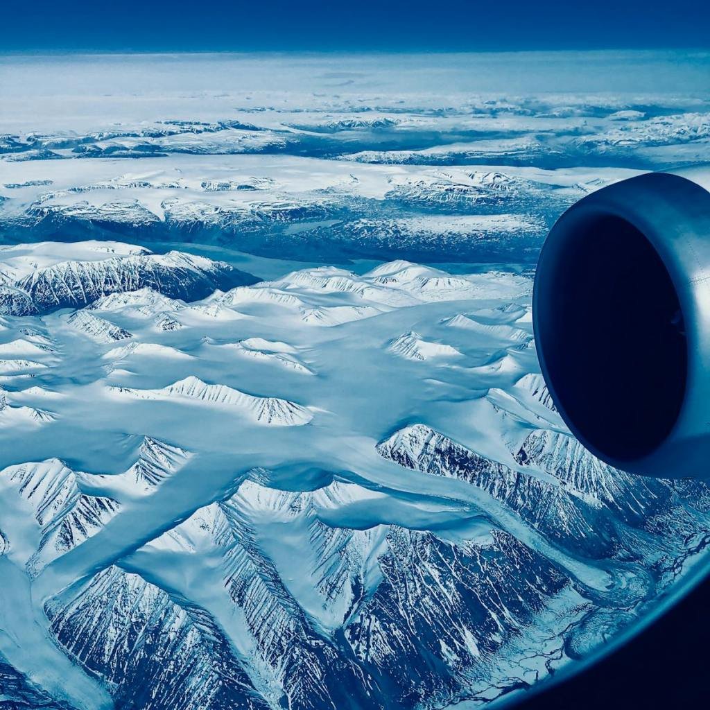 Captivating aerial view of snow-covered mountain peaks from an airplane window.