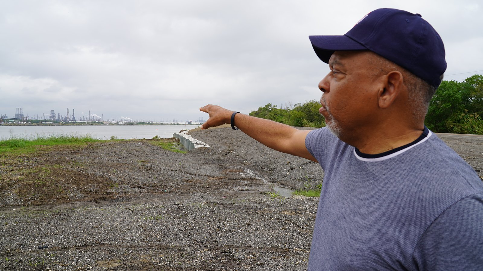 A man in a baseball hat points at a nearby beach