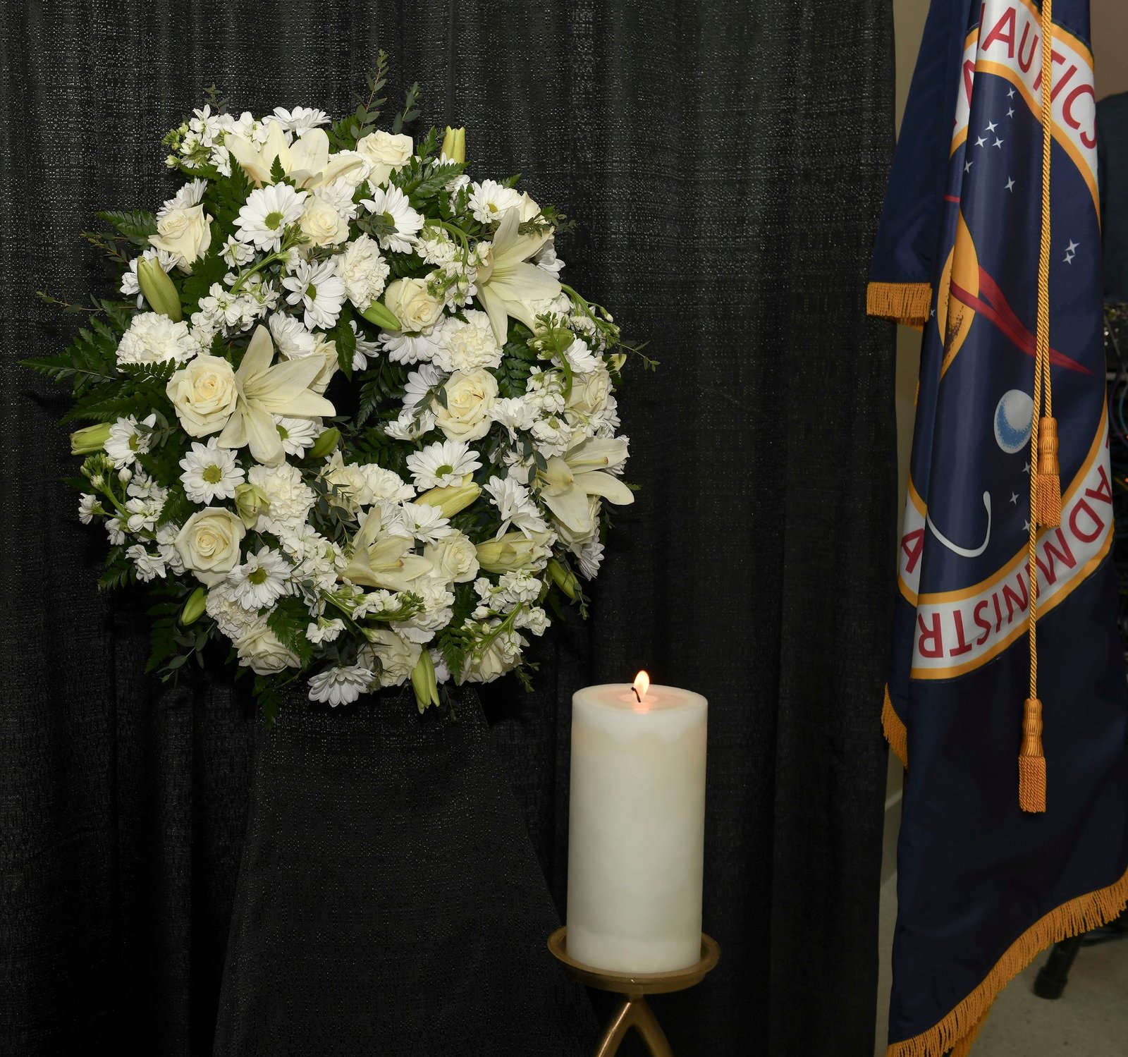 Marshall Space Flight Center Day of Remembrance photo featuring a white candle, wreath of flowers and the NASA flag.