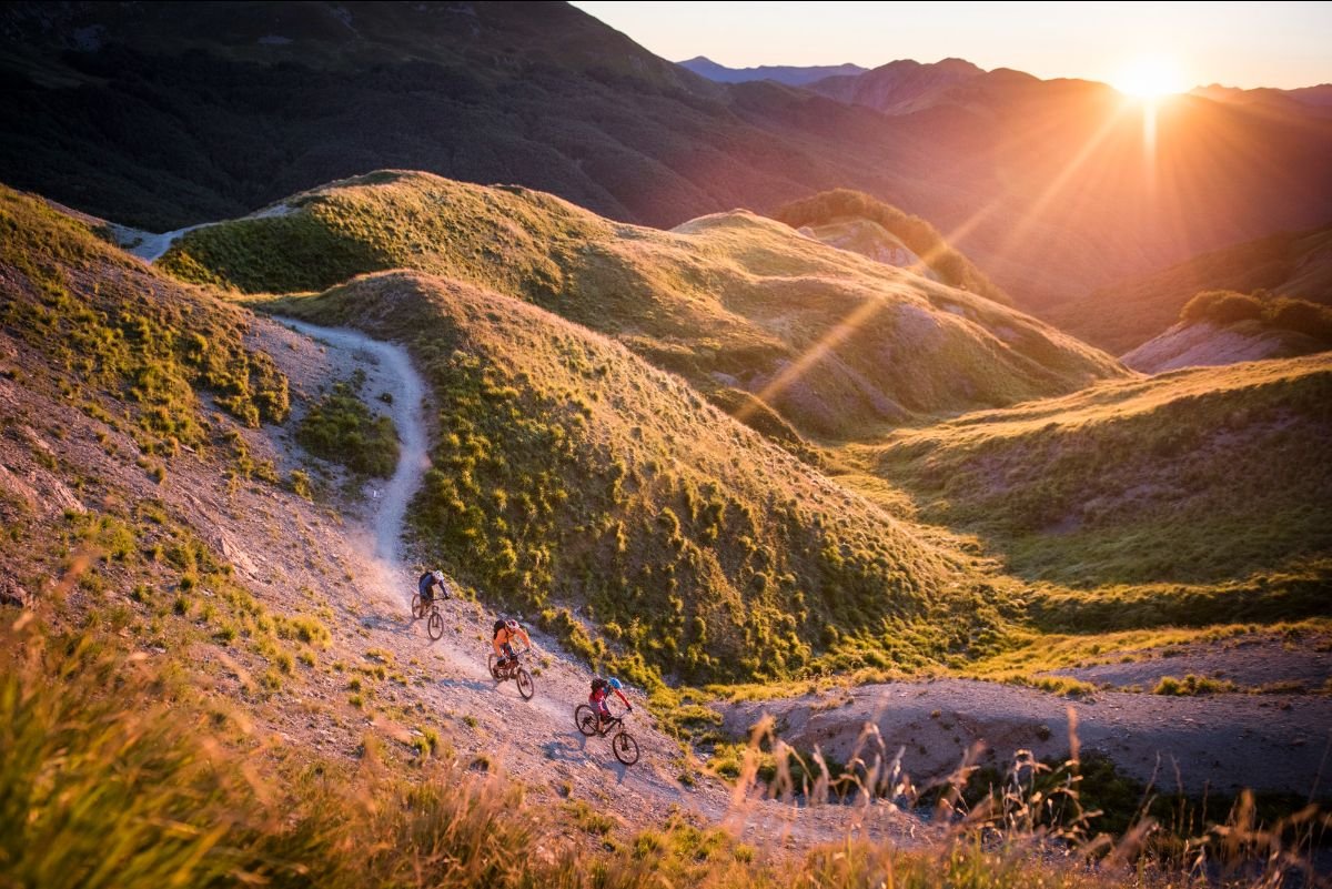 trail bikers cycle through a mountain valley