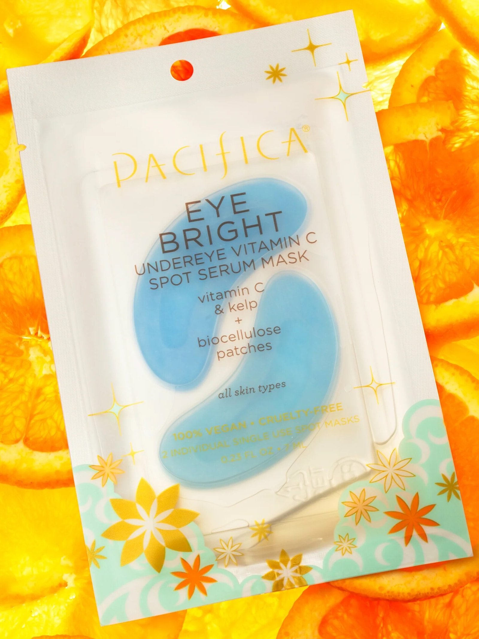 Packaging of Pacifica Eye Bright Undereye Vitamin C Spot Serum Mask with blue patches, against a background of sliced oranges.