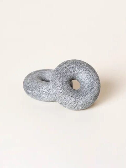 Two gray stone rings with central holes, resting on a neutral surface.