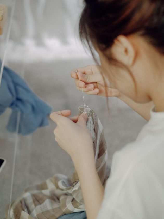 Woman doing the slow fashion practice of mending a garment