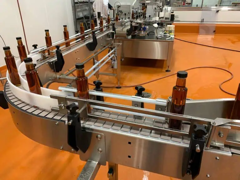 Automated maple syrup filling line with glass bottles on a conveyor belt.