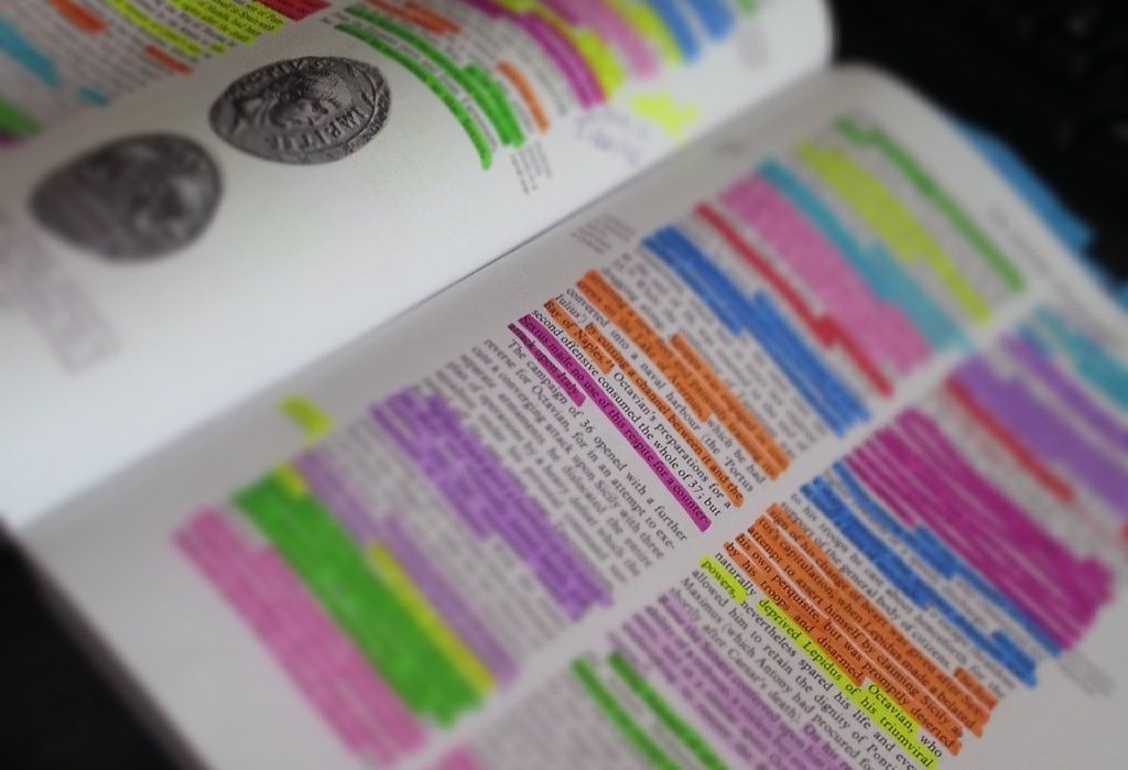 A school textbook with passages of text highlighted in several different colours. 