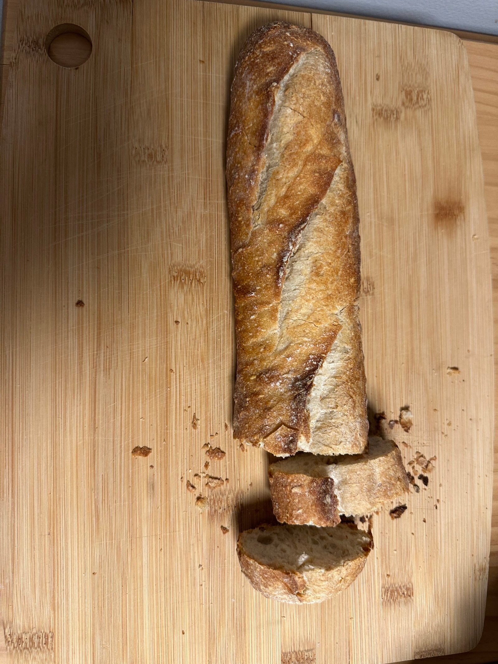 Sliced crusty baguette on a wooden cutting board.