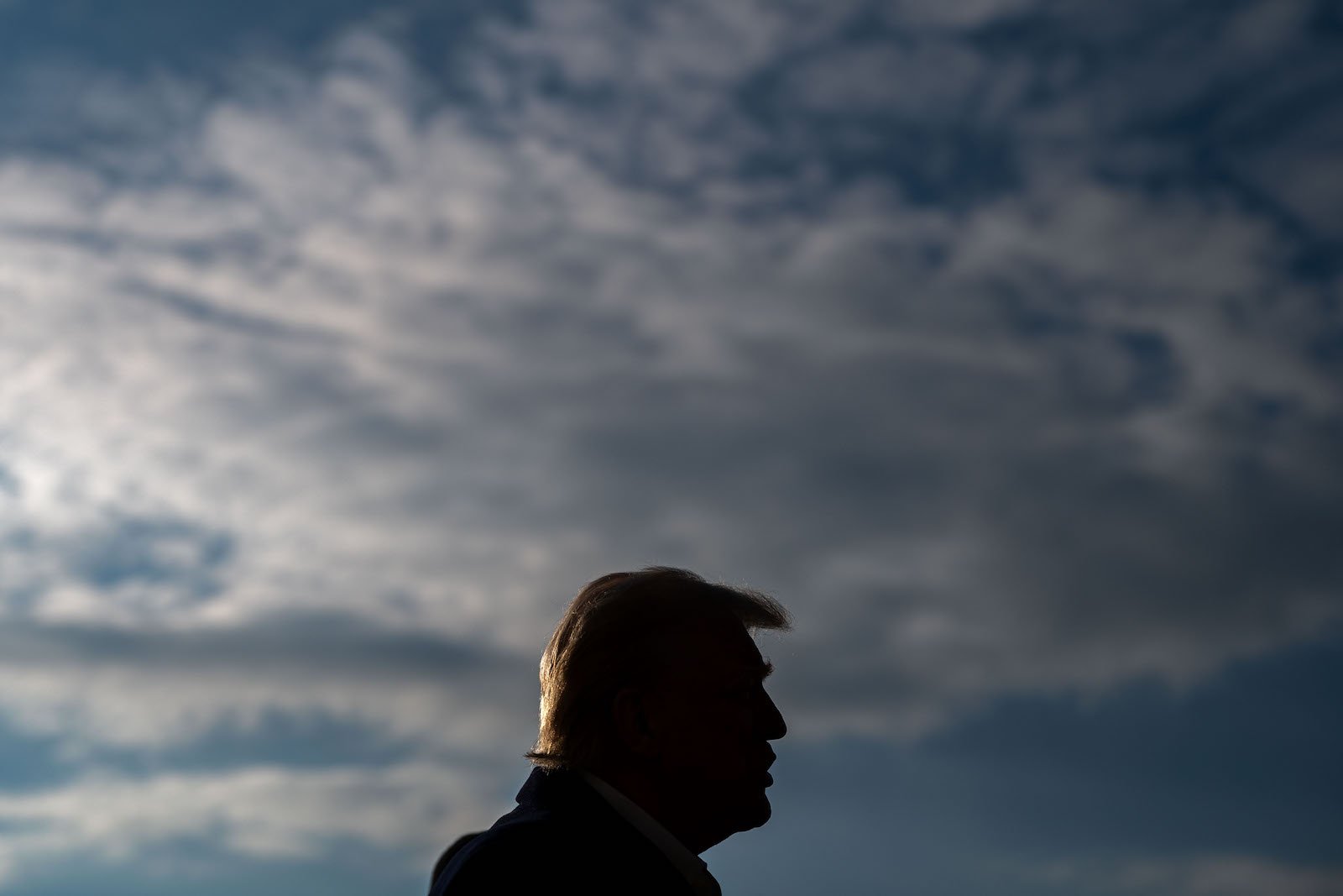 President Trump silhouetted against a cloudy sky