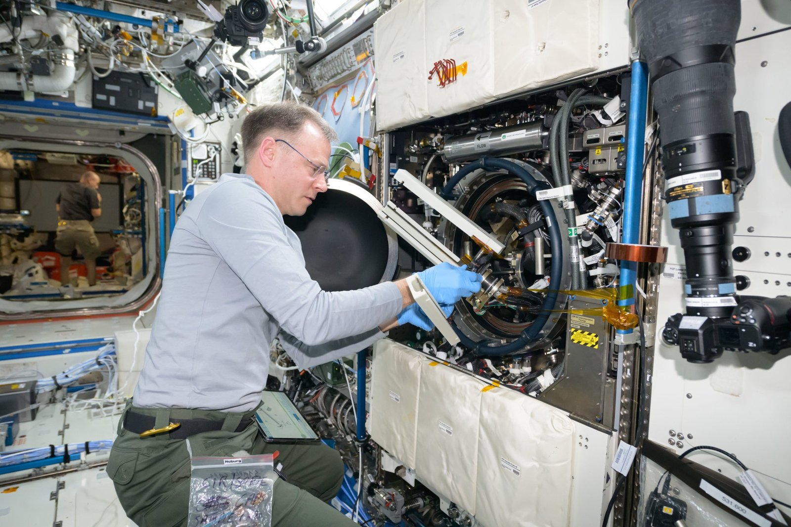 Astronaut Nick Hague swaps samples of materials to observe how they burn in weightlessness.