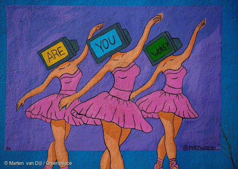 A mural with a purple and blue background depicting 3 ballerinas wearing pink dresses. The dancers have TVs as heads which each contain one word, spelling out "ARE YOU WOKE?" together.
