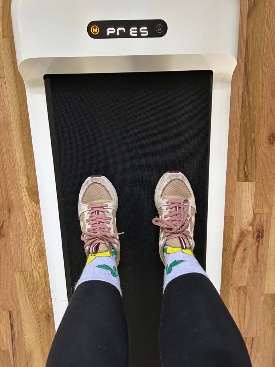 Person wearing patterned socks and sneakers standing on a treadmill.