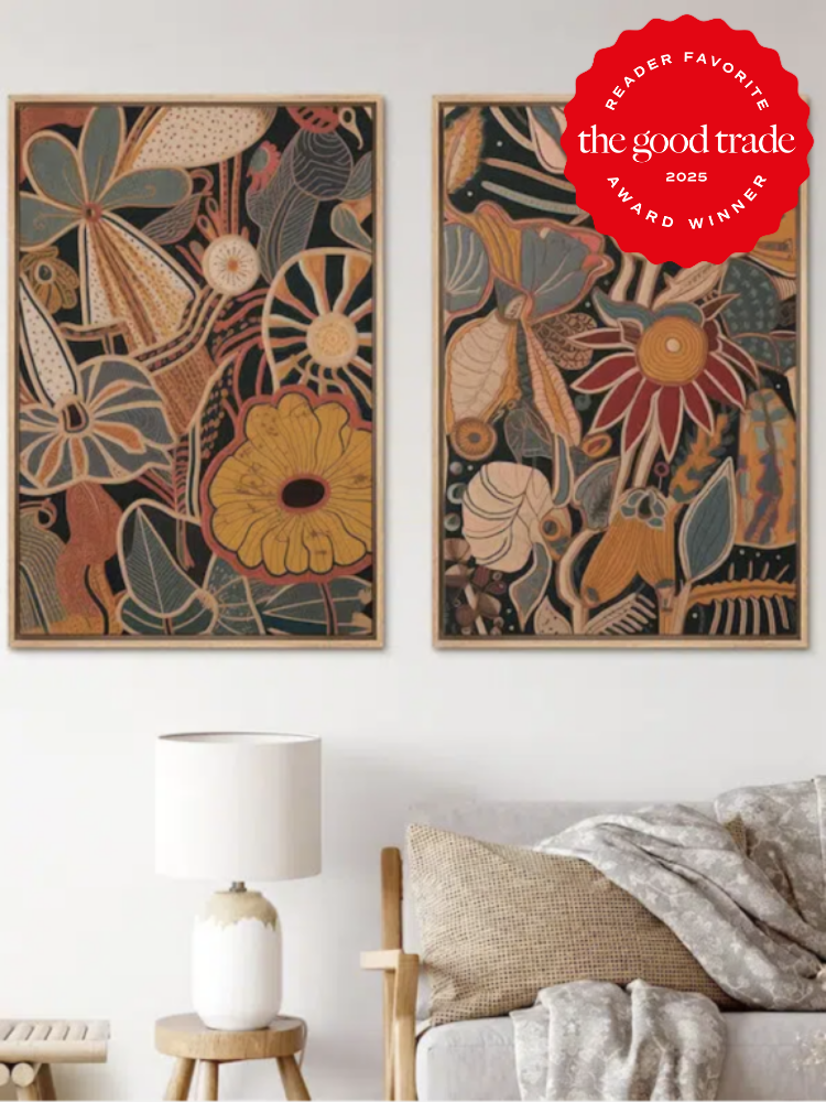 Two floral-themed framed artworks hang above a neutral-toned couch with pillows. A lamp sits on a side table. A "Reader Favorite" award badge is on the wall.
