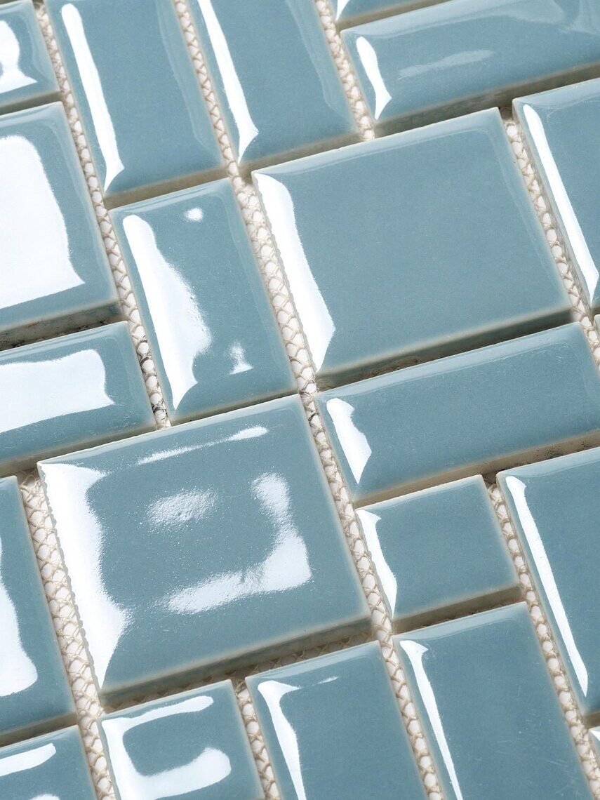 Close-up of glossy light blue square tiles with a slightly raised surface, arranged in a grid pattern.