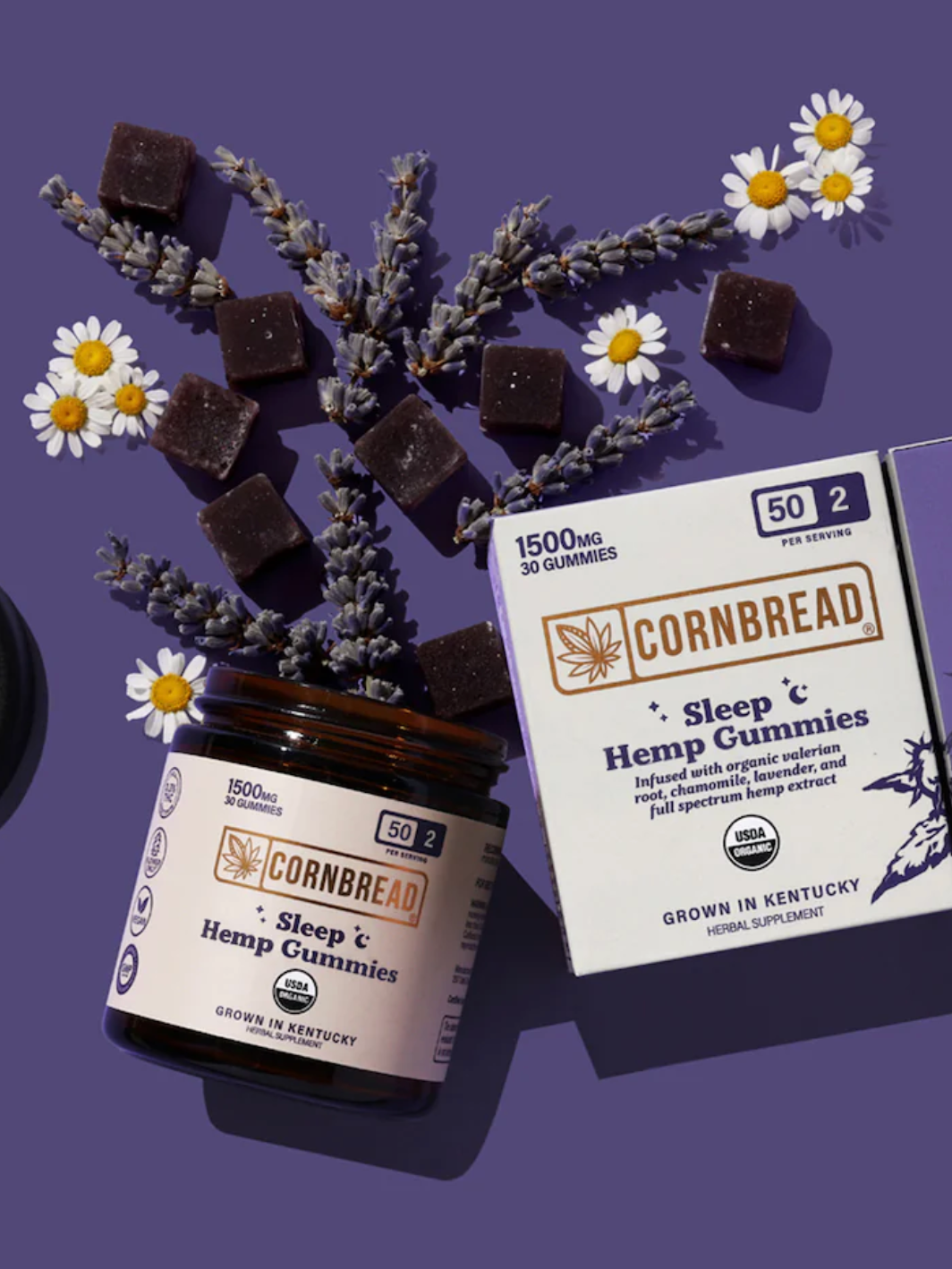 A jar and box of Cornbread Hemp Sleep Gummies are arranged with lavender sprigs, chamomile flowers, and several gummies on a purple background.