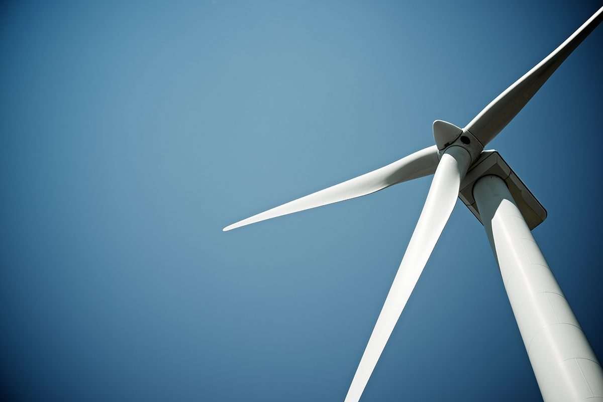 Wind turbine blades seen from slightly below, against blue sky