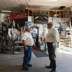 Two men talking to each other in a muffler shop.