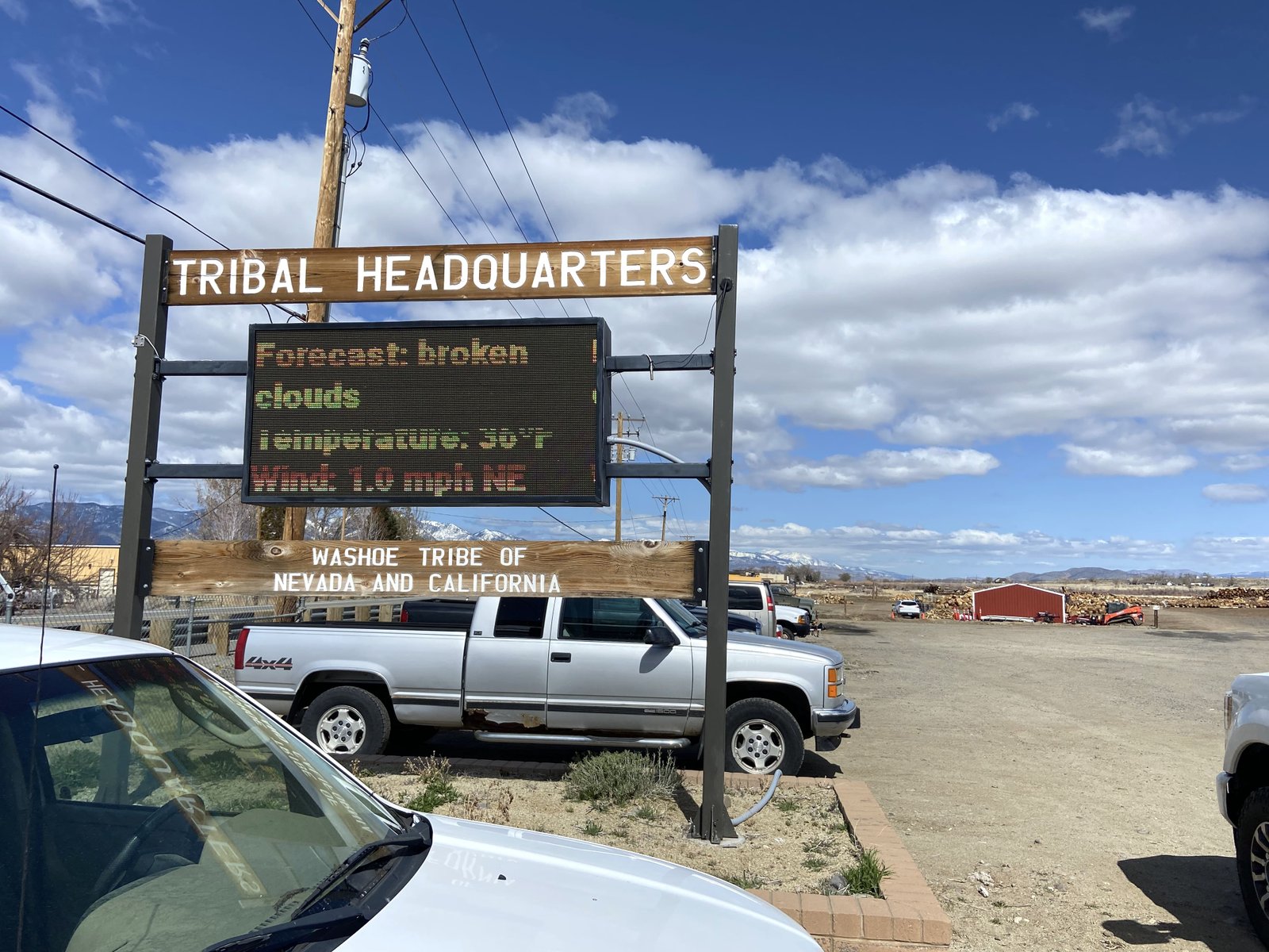 A sign that reads tribal headquarters with trucks sitting next to it