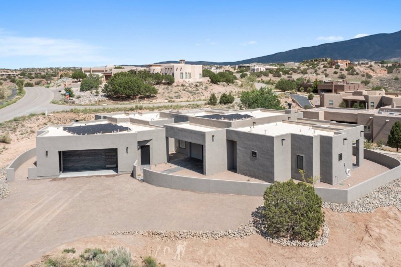 exterior view of large, modern adobe-style home made with prefab SIPs, desert location, solar panel on roof; SIP panel suppliers: Premier Building Systems