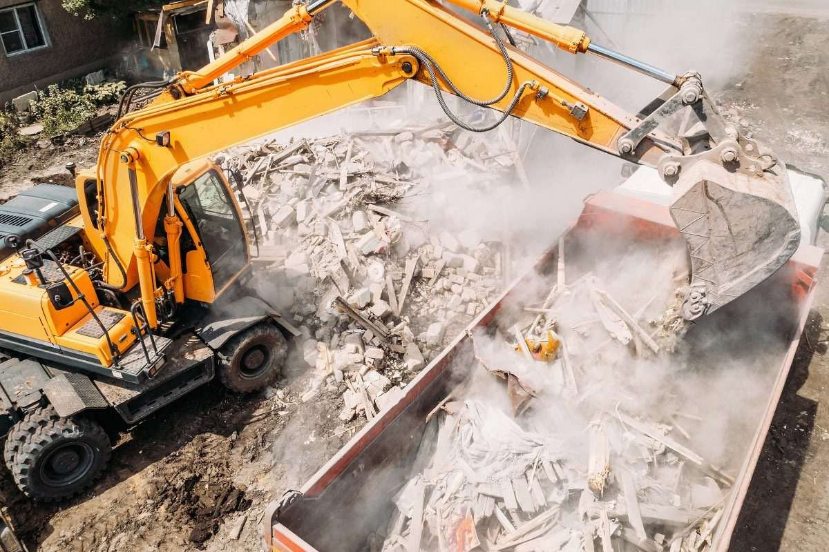 Excavator loads construction waste into a truck
