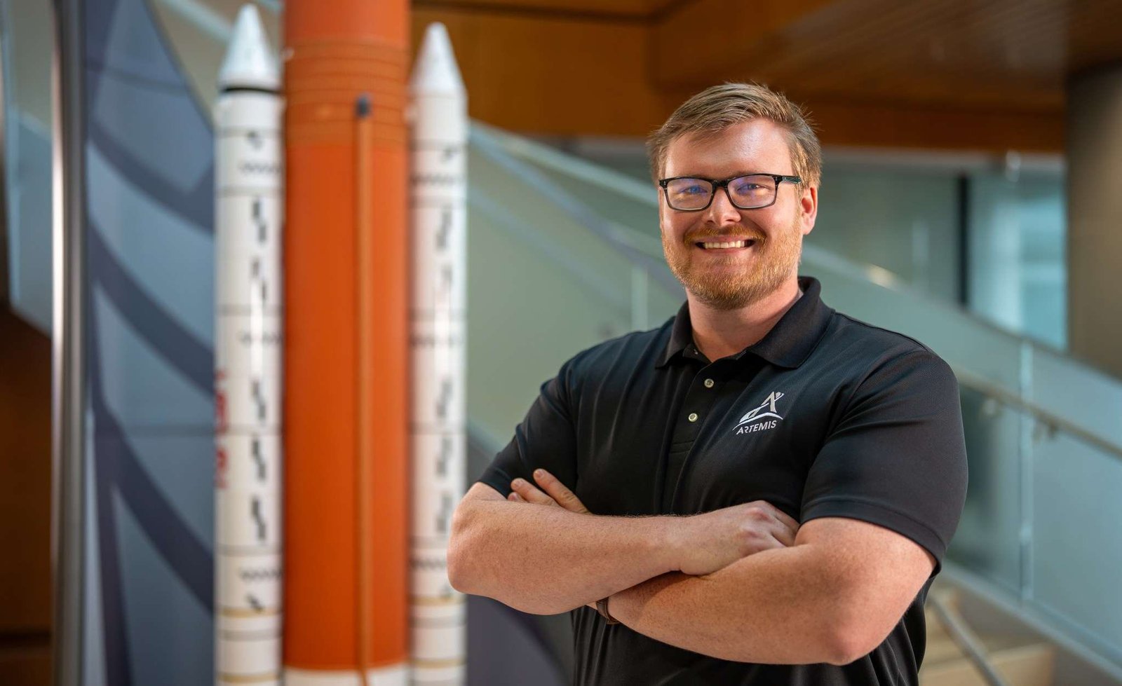 Patrick Junen stands beside a model of the Space Launch System.