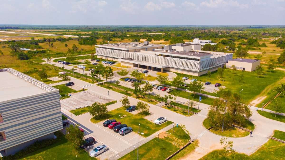 Aerial view of the Pan Atlantic University campus in Lagos, Nigeria, characterised by a small number of large buildings, visible as flat, cuboidal structures, white or light-coloured, arranged within a semi-arid, flat landscape