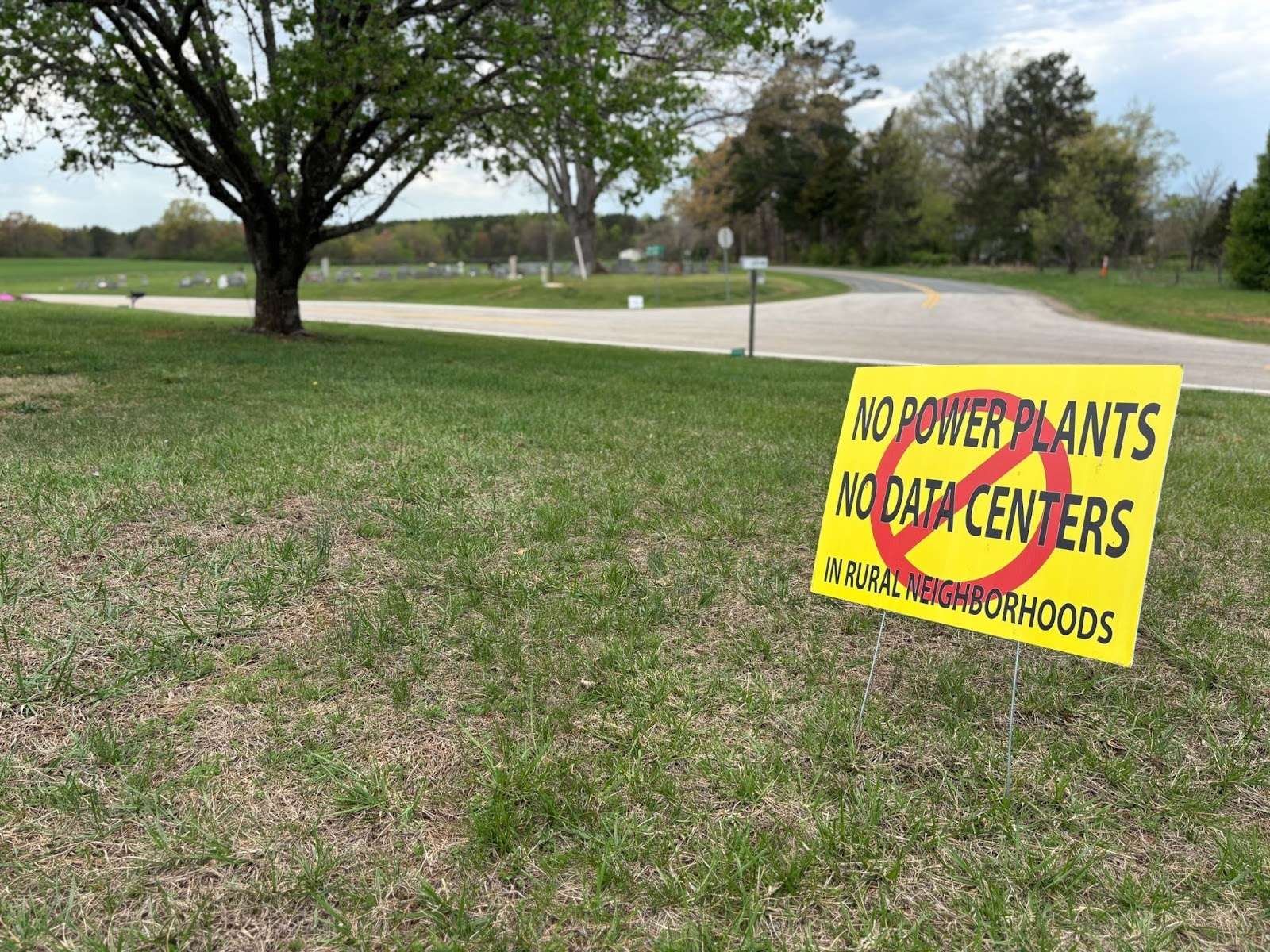 A yellow sign in a field that reads no power plants no data centers in rural neighborhoods