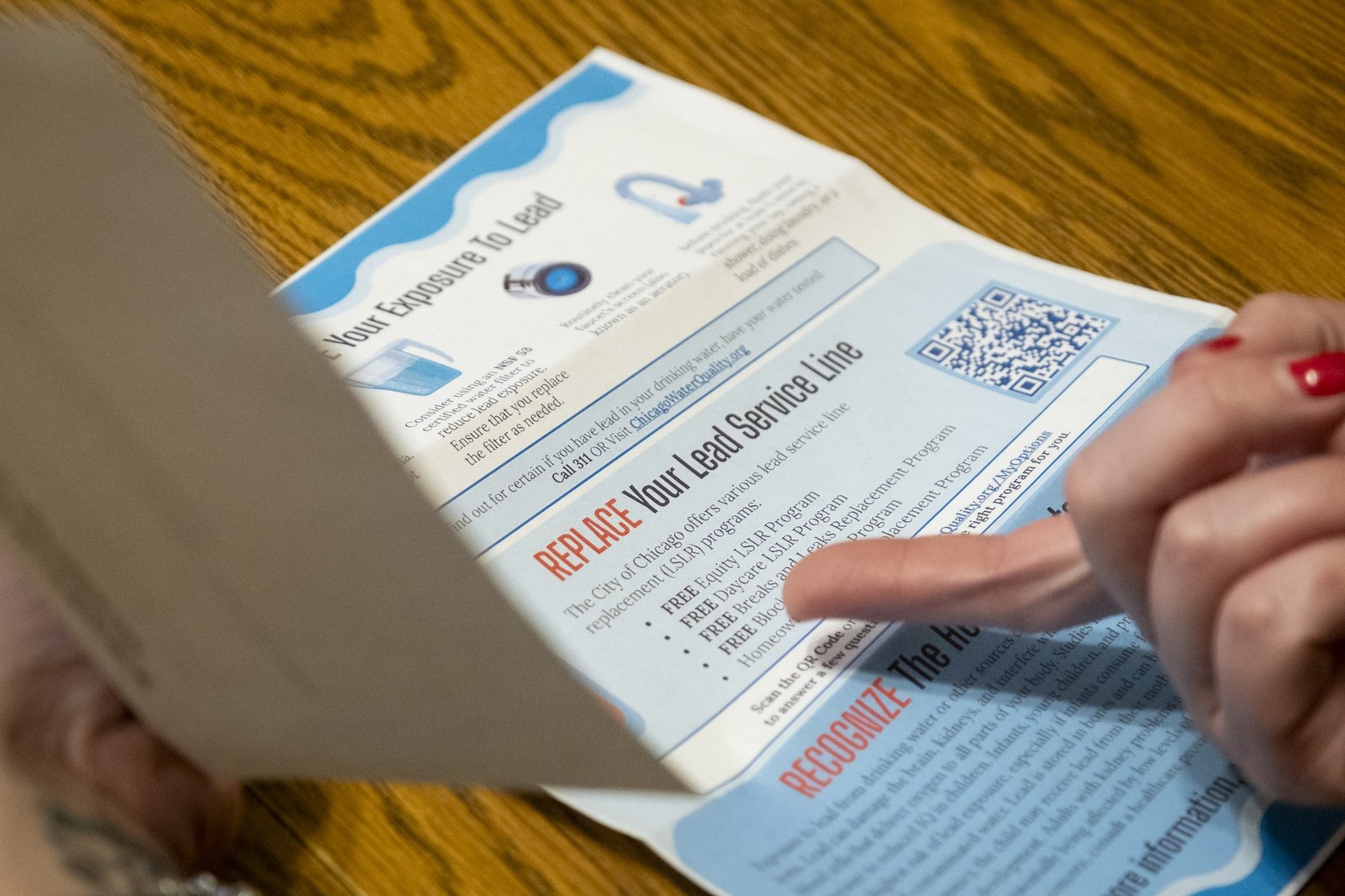 a hand points to information about lead contamination on a flyer