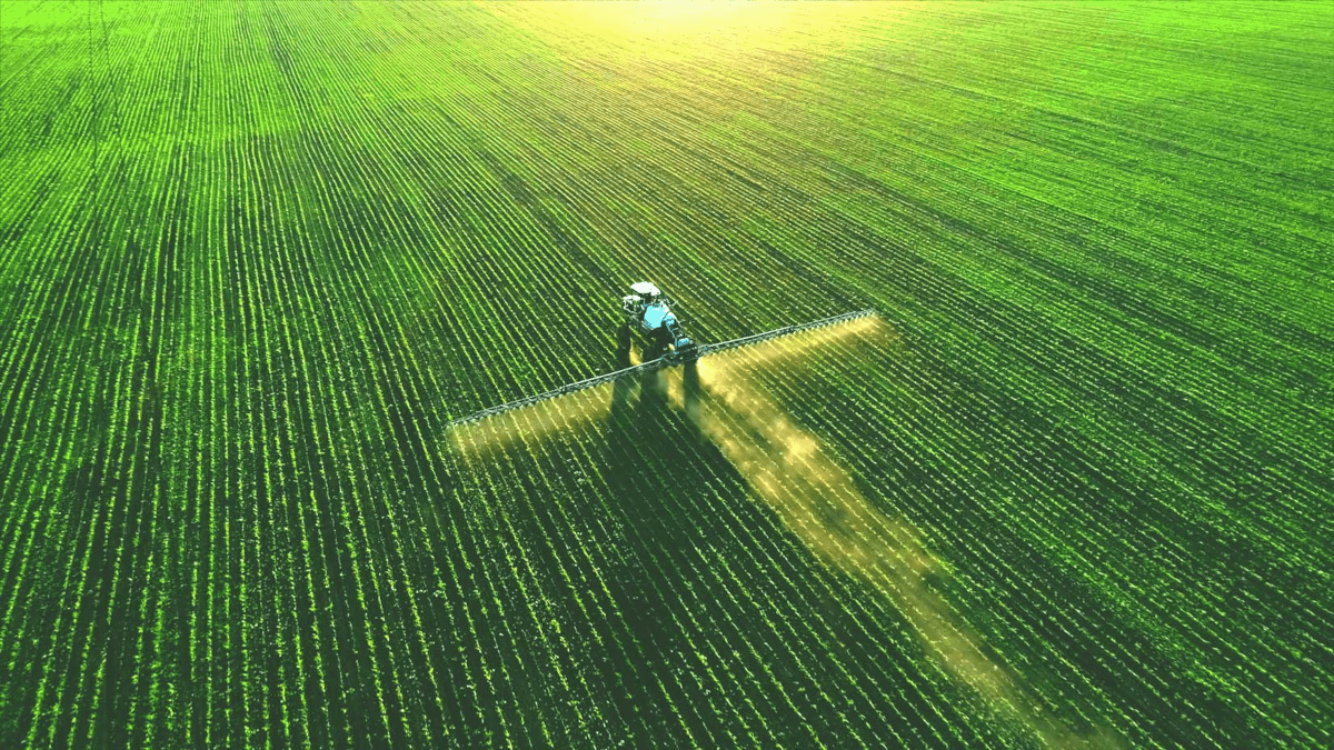 Aerial view of crop-spraying vehicle set against green crop-laden field