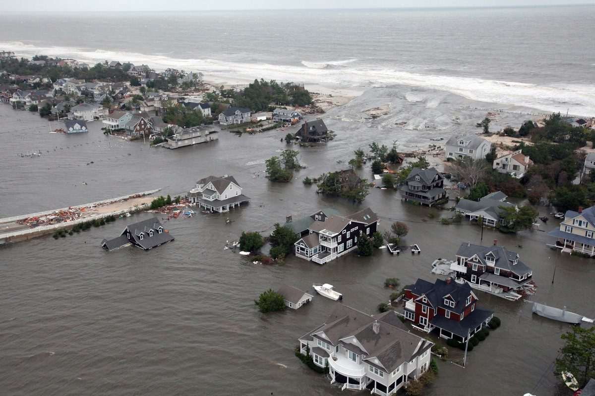 Aerial view showing flooded coastal region with wooden houses and Cape-Cod-style cottages protruding from the water in various places