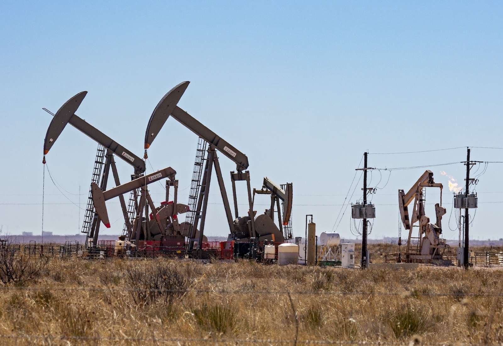 Rust-colored pumpjacks against a clear blue sky