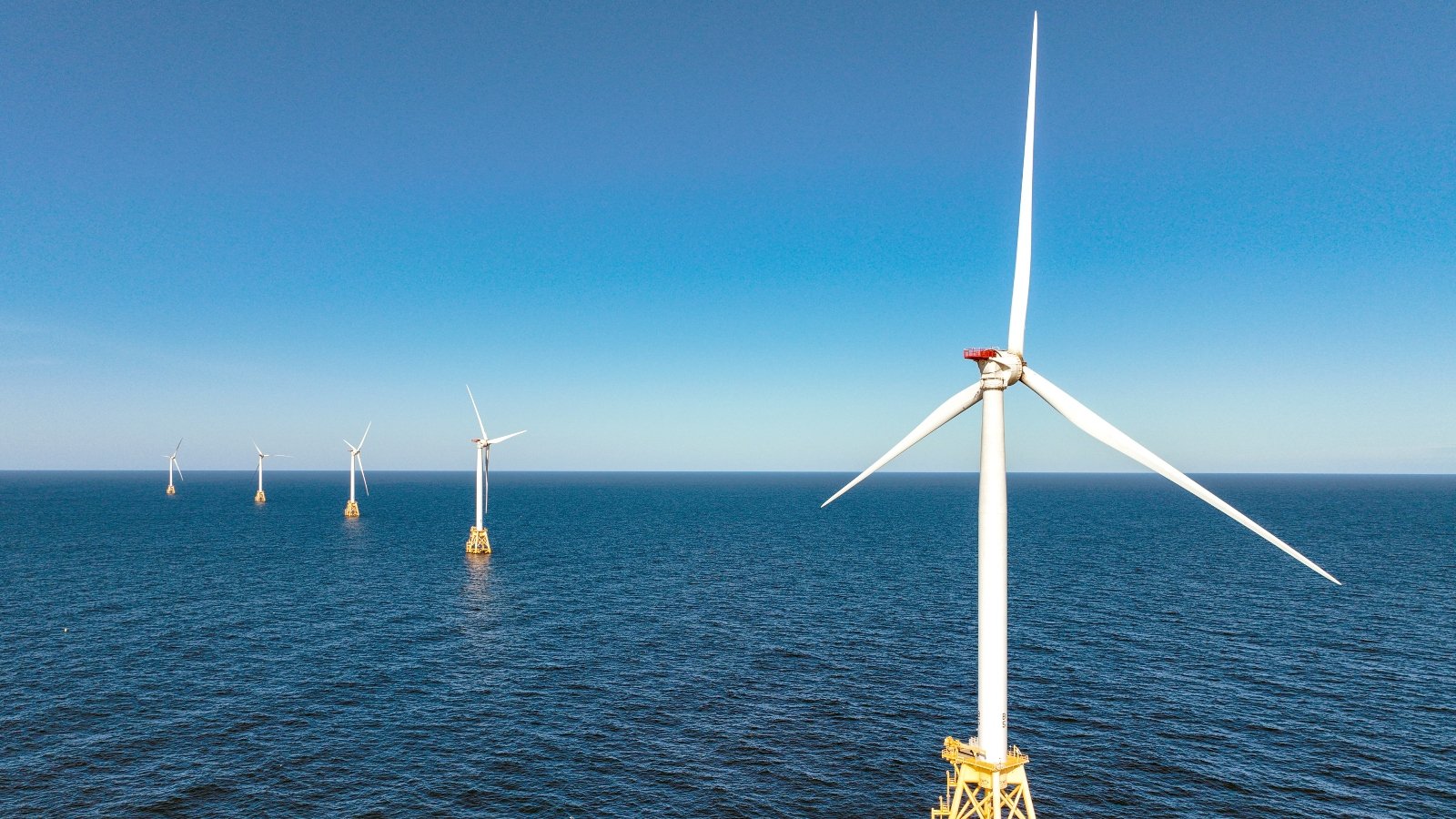 Several wind turbines stand in the middle of the ocean