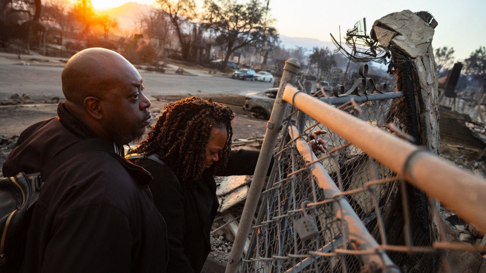 A couple looks at the charred remains of their home burned in the Eaton Fire in Altadena, California, January 9, 2025. Massive wildfires that engulfed whole neighborhoods and displaced thousands in Los Angeles remained totally uncontained January 9, 2025, authorities said, as US National Guard soldiers readied to hit the streets to help quell disorder. Swaths of the United States' second-largest city lay in ruins, with smoke blanketing the sky and an acrid smell pervading almost every building.