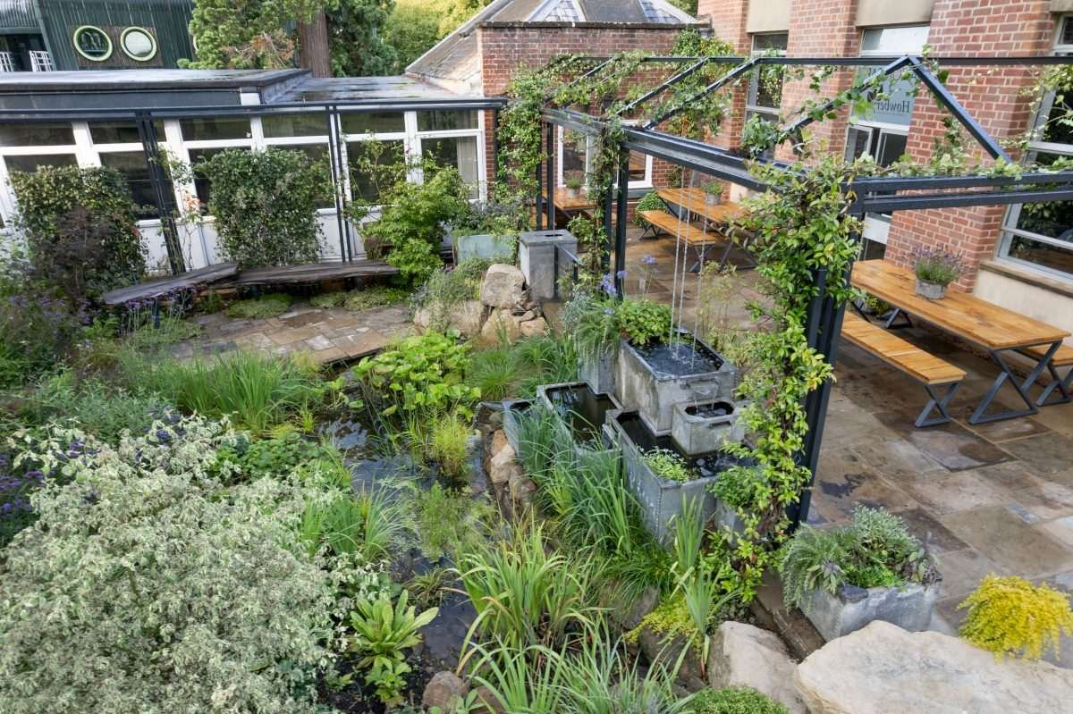 An elaborate garden with cuboidal hanging plant pots, foliage and water features