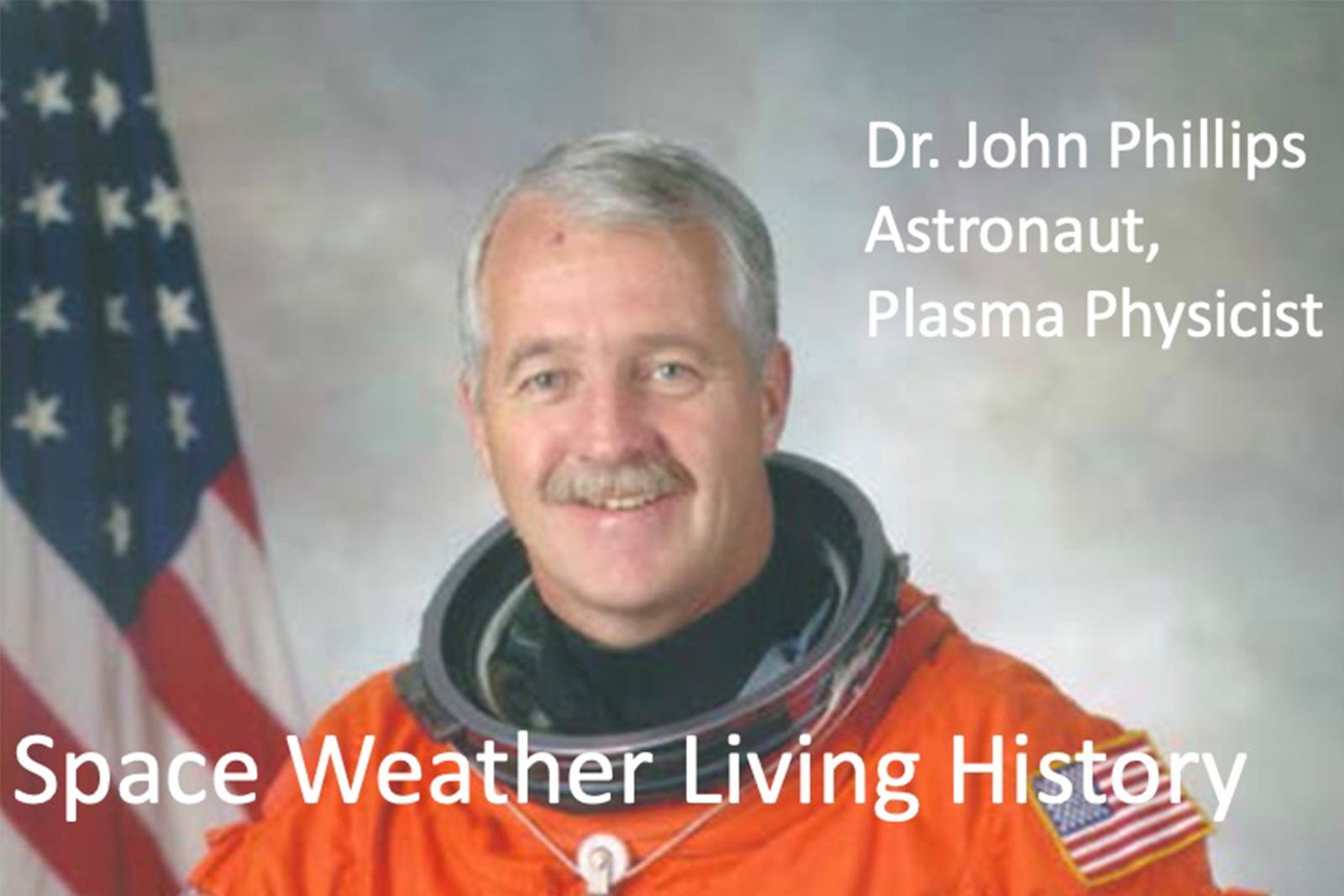 A photo of John Phillips in his orange astronaut suit with the American flag on the left.