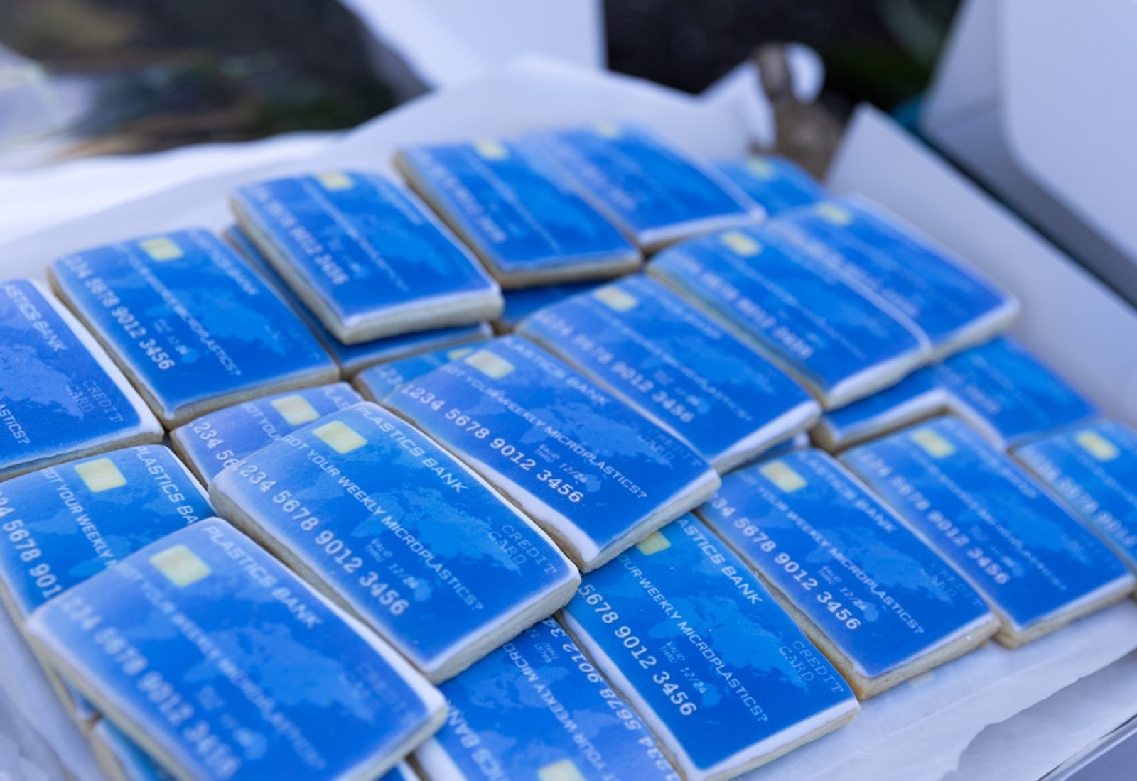 View of cookies designed to look like blue credit cards, lined up and stacked in a box