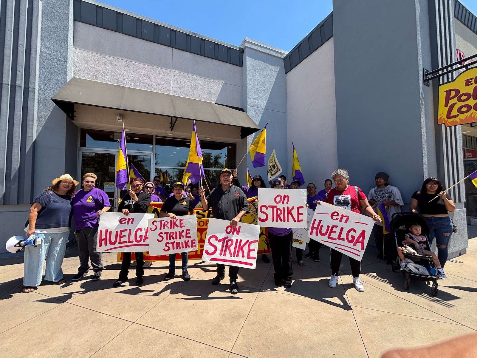 A group of fast-food workers stand outside an El Pollo Loco holding strike signs