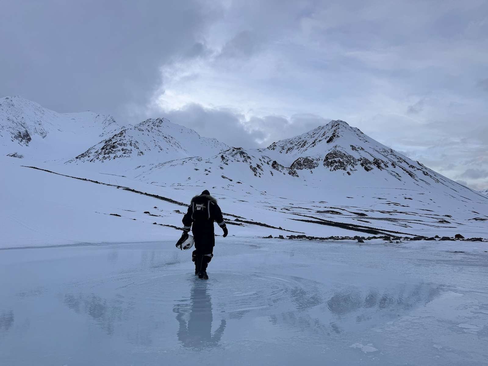 A lone human figure walks on melting ice in the Arctic