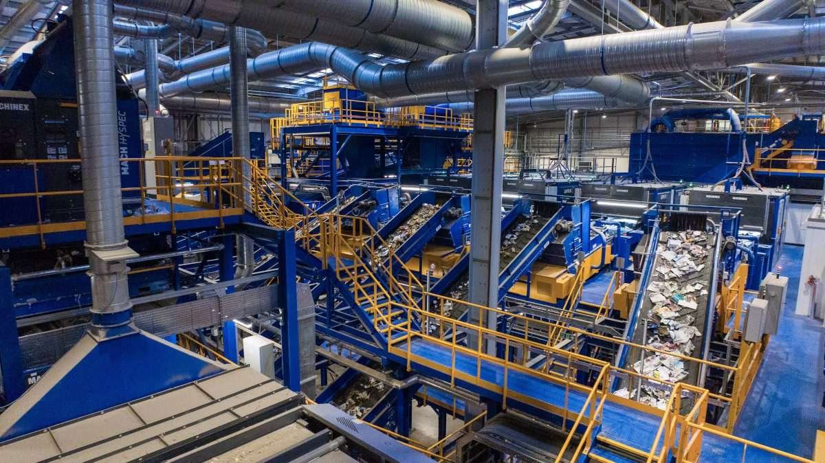 Interior of an industrial facility comprising a complex arrangement of steeply inclined conveyor belts, walkways and other structures - a materials recycling facility
