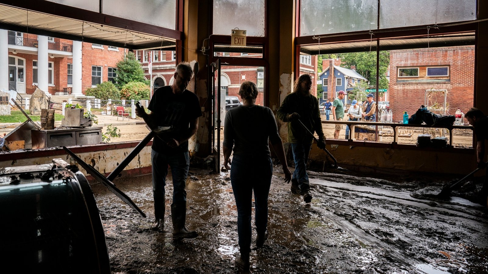 Owners, volunteers, and community members help clean up mud and debris at a coffee shop in Marshall, North Carolina after Hurricane Helene in 2024.