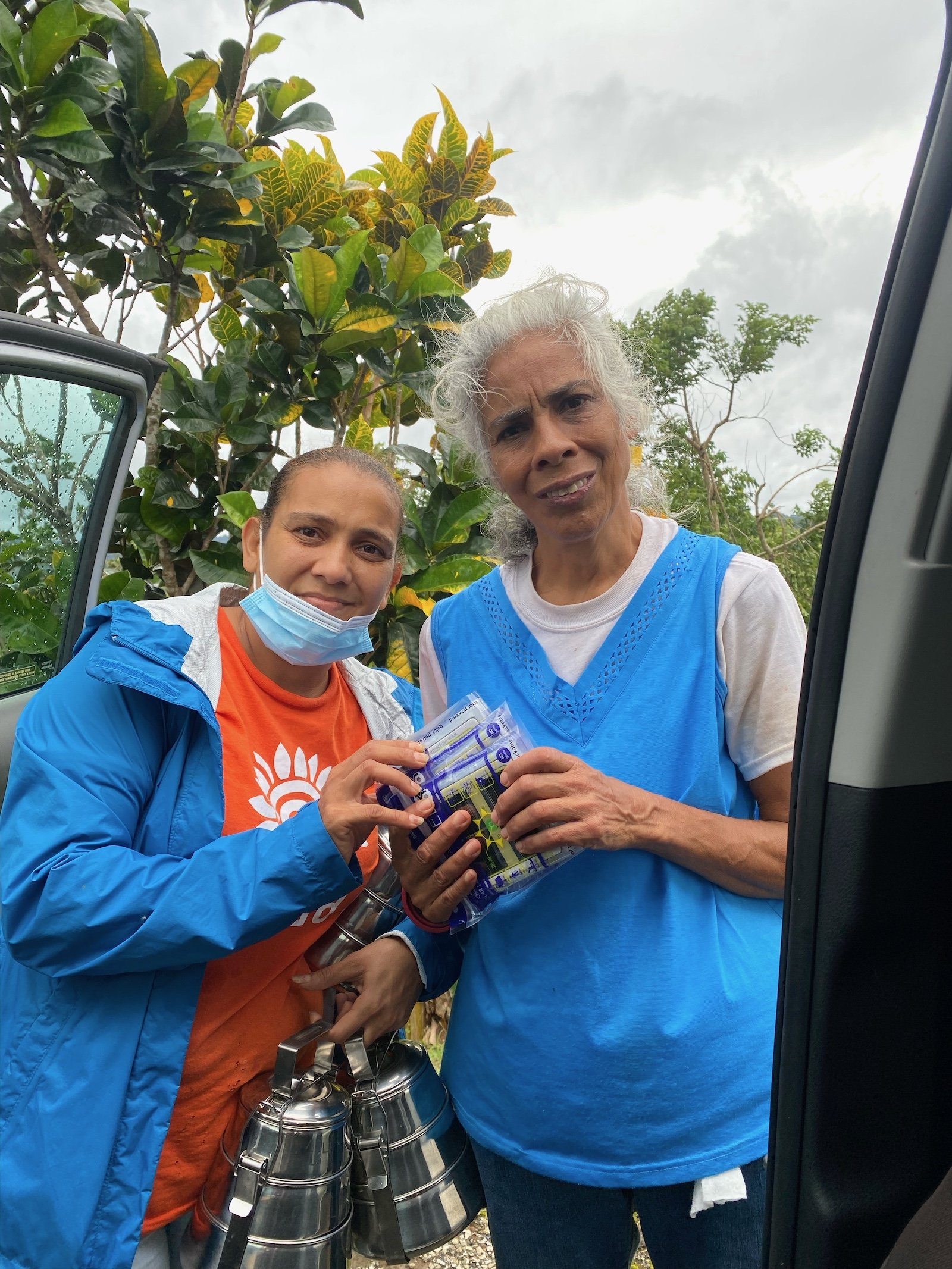Two women stand with water filtration systems