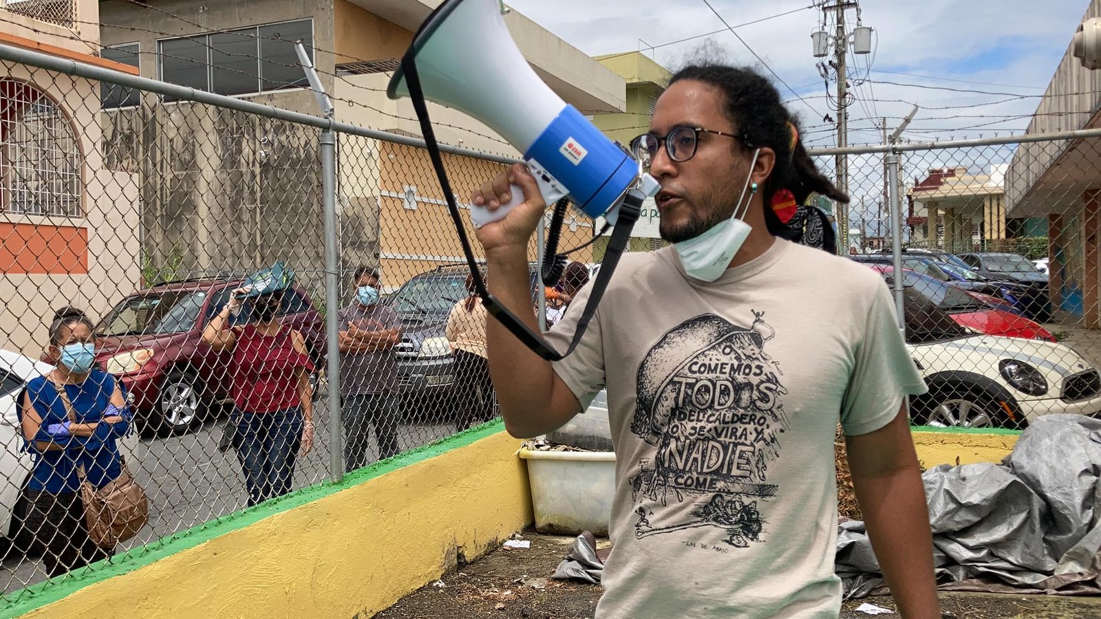 A man holds a blowhorn while walking past a group of people on a city street