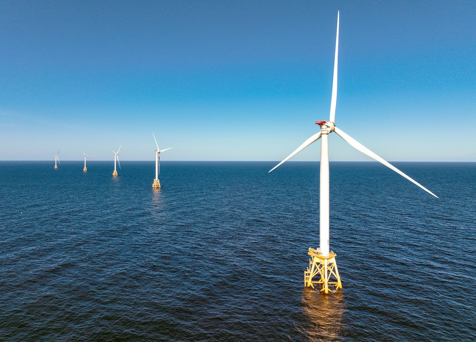 Windmills offshore in front of a blue sky