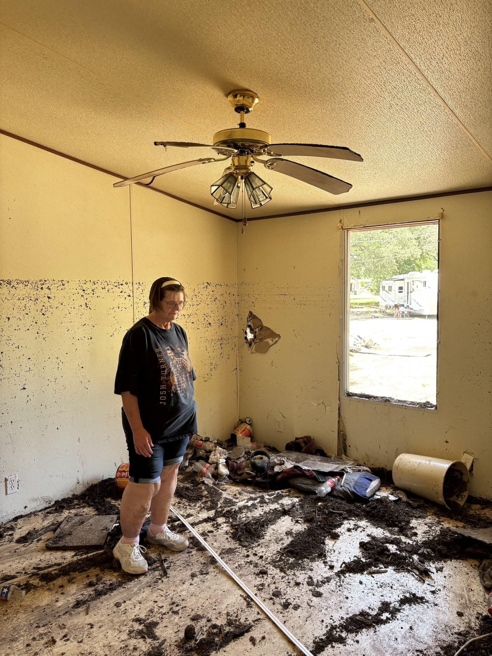 A woman stands inside a severely flood-damaged house