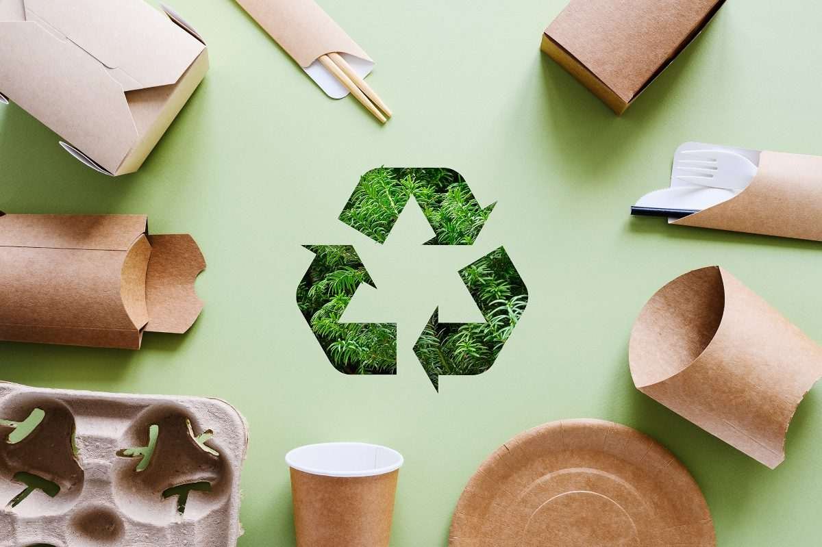 Different types of product packaging (all unbranded) arranged in a circle with a recycling logo in the middle
