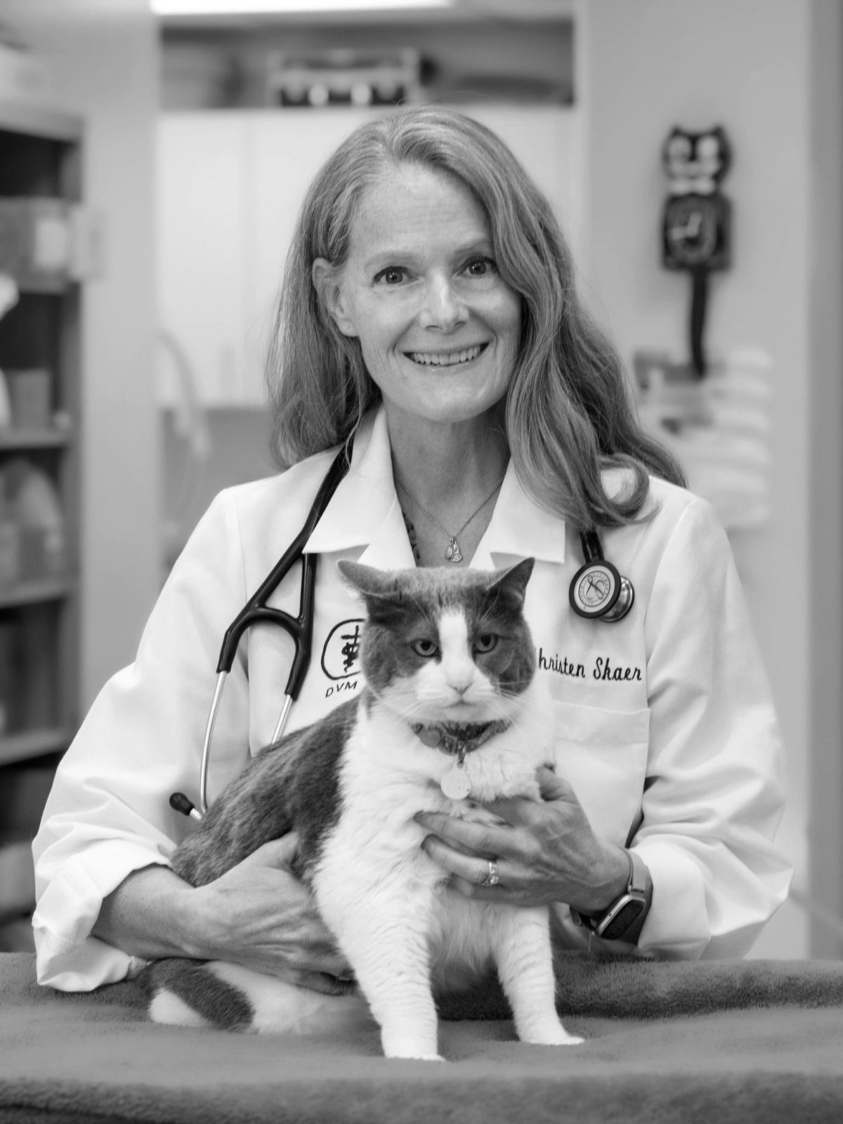 a woman in a white labcoat holds a cat