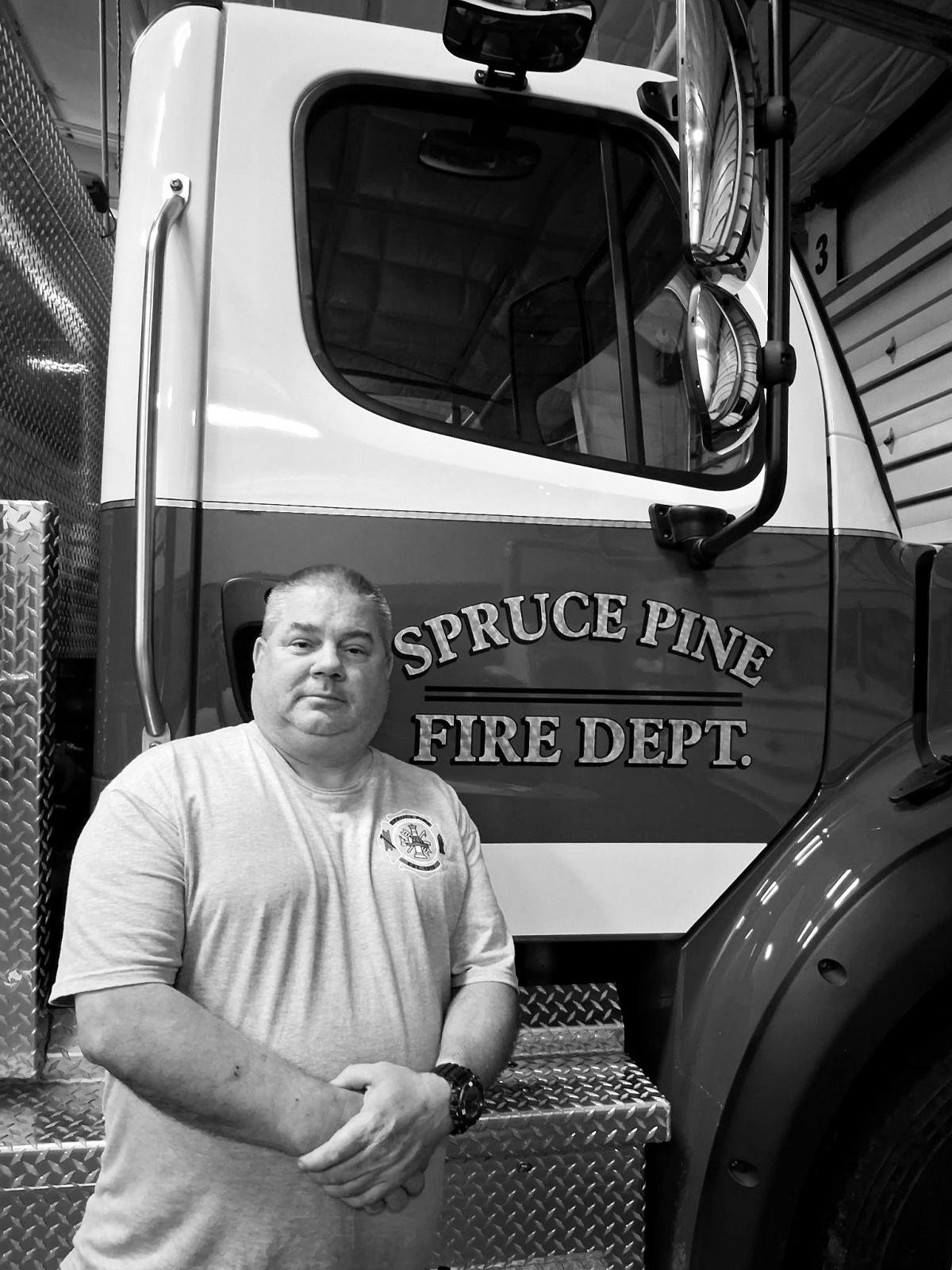 a black and white photo of a man standing next to a fire truck