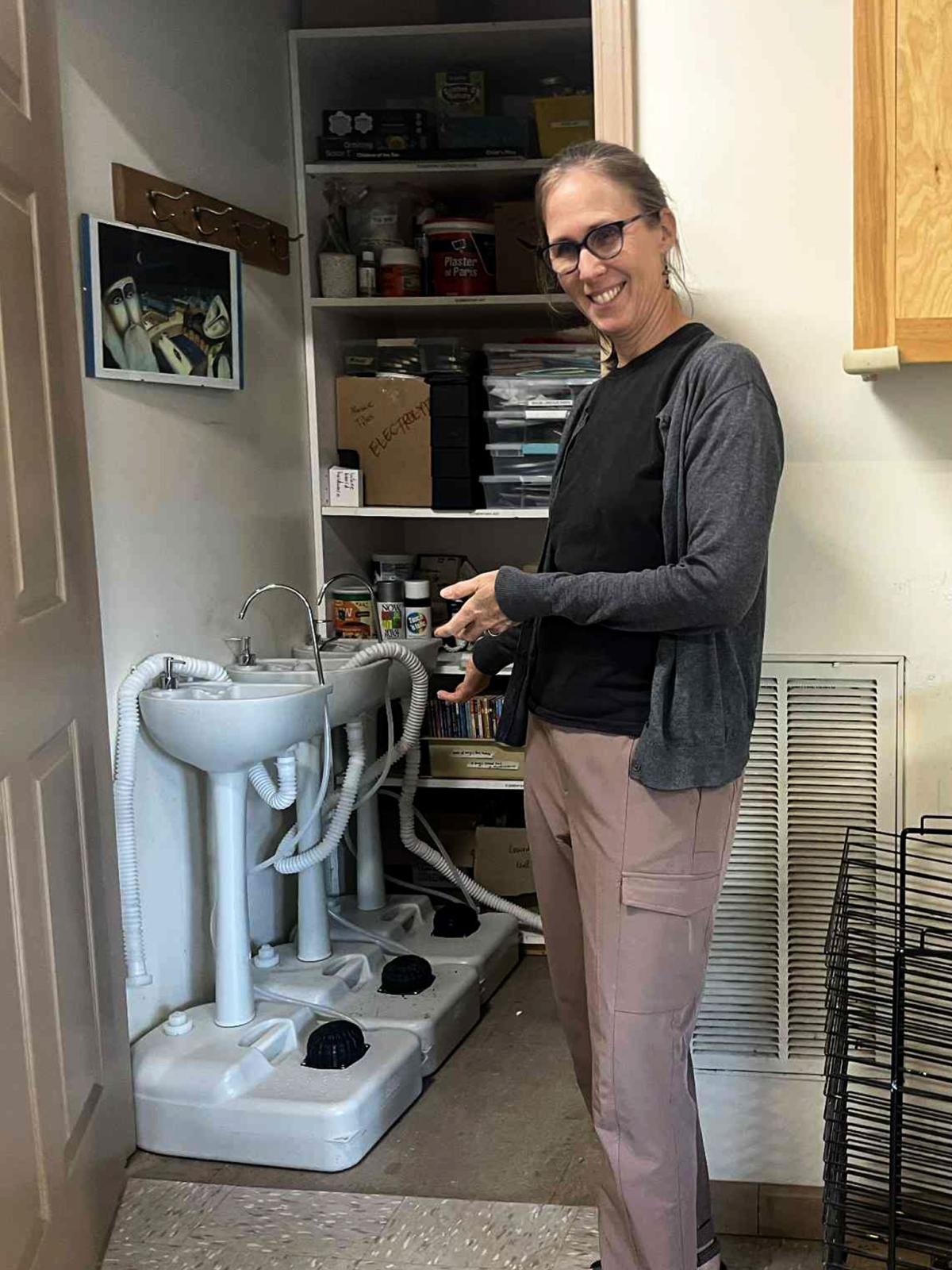 Photo of Jennifer Rambo standing beside temporary handwashing stations