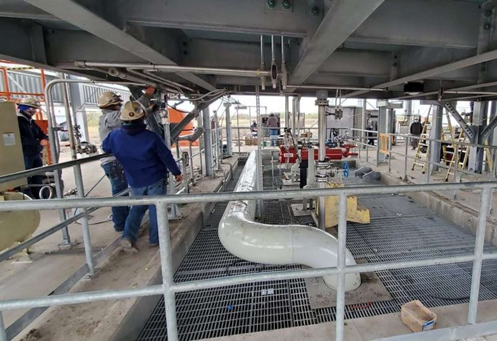 Workers around a pipe leading into the ground
